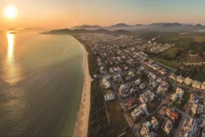 Jurerê, vista aérea de uma praia e o bairro de Jurerê ao pôr do sol.