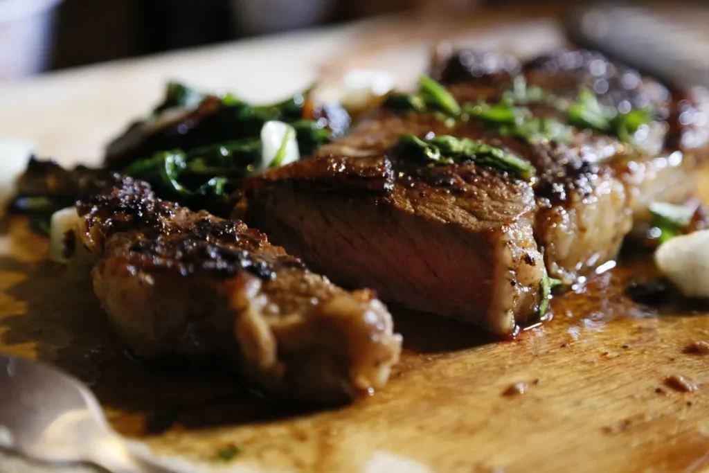 Detalhe de um corte de carne grelhada e fatiada servida em uma tábua de madeira.
