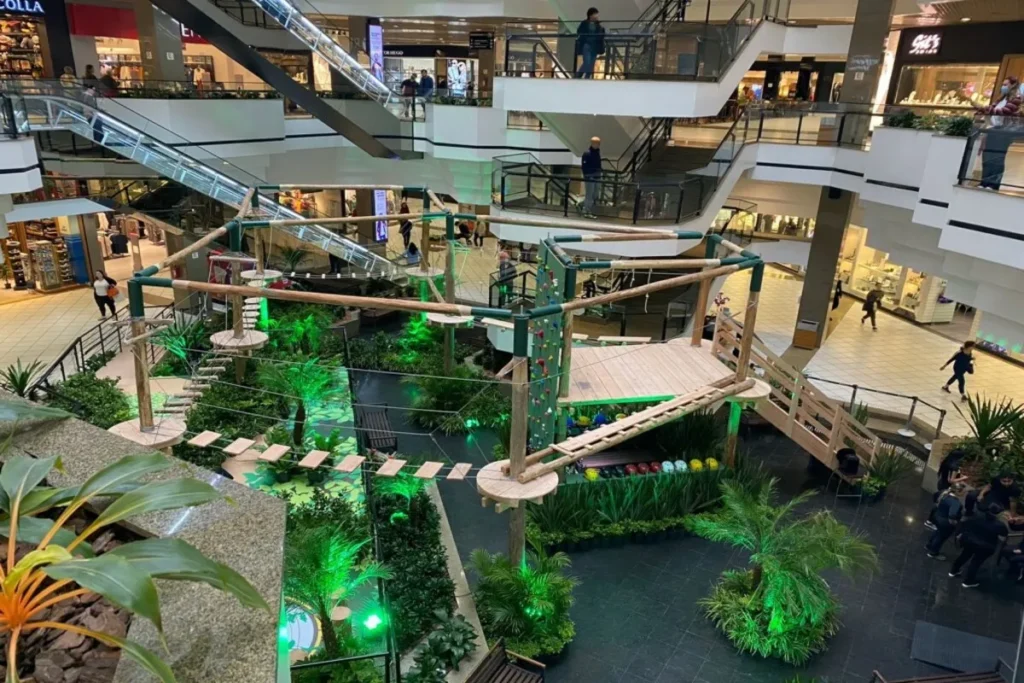Vista do interior do Beiramar Shopping, em Florianópolis. O vão central abriga um parque de aventura ou circuito de arvorismo temporário, com plataformas e pontes de corda.