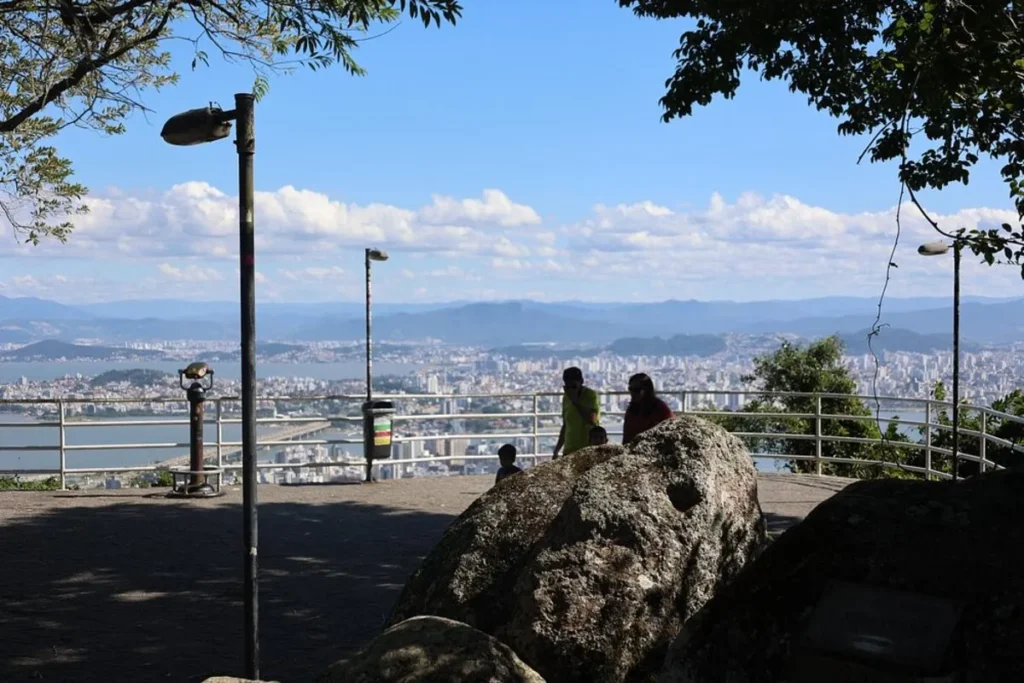 Vista panorâmica de Florianópolis a partir do Mirante do Morro da Cruz, com pessoas apreciando a paisagem