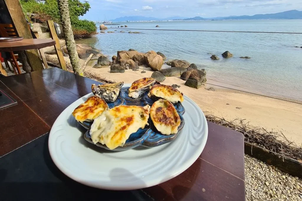 Prato com ostras gratinadas em um restaurante com vista para a praia de Santo Antônio de Lisboa, em Florianópolis.