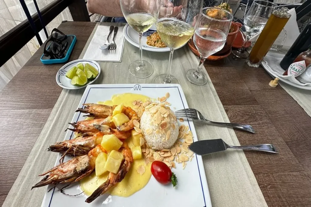 Prato gourmet com camarões, arroz e amêndoas em um restaurante à beira-mar em Santo Antônio de Lisboa, Florianópolis.