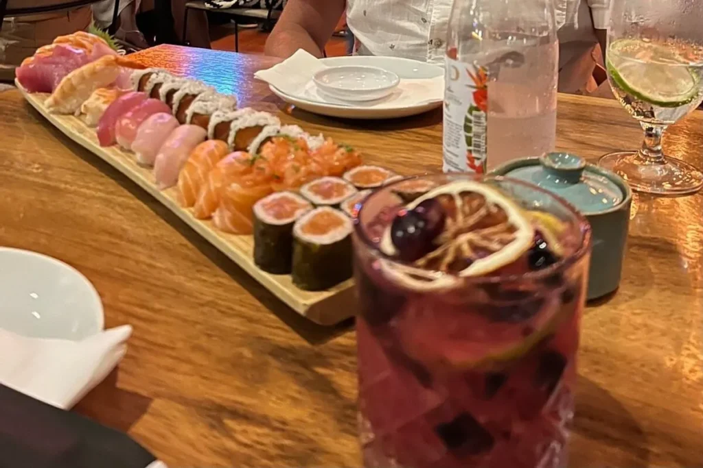 Prato de sushi com sashimis, niguiris e makis acompanhado de drink em restaurante japonês em Florianópolis