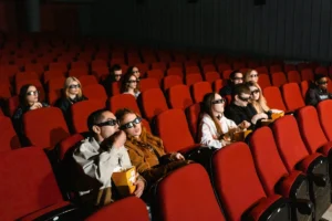 Público assistindo a um filme 3D em uma sala de cinema com poltronas vermelhas em Florianópolis
